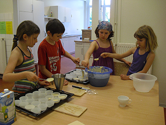 Vier Kinder backen zusammen Muffins