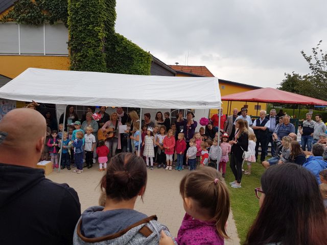 Die Kinder stehen und einem weißen Zelt und singen