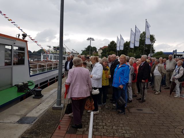 Eine Gruppe Senioren steht vor dem Schiff und wartet